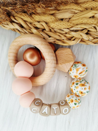 Bijtring met naam bloem oranje, metallic brons, light pink 